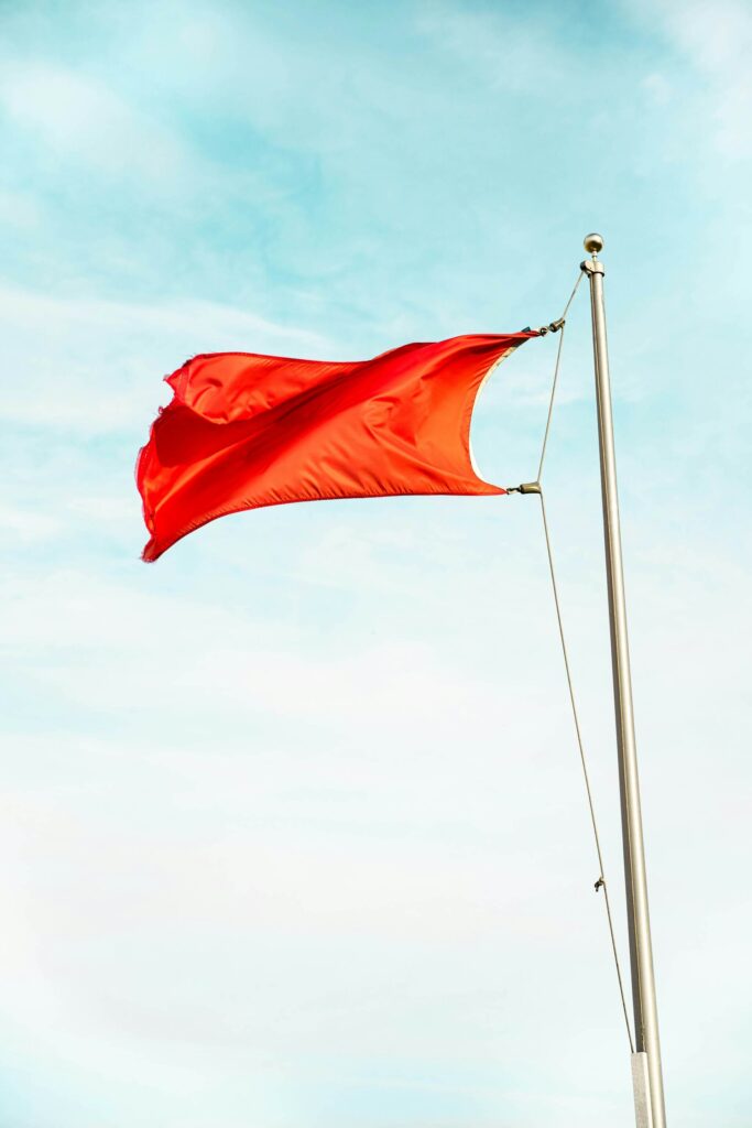 A red flag on a flagpole blowing in the wind.
