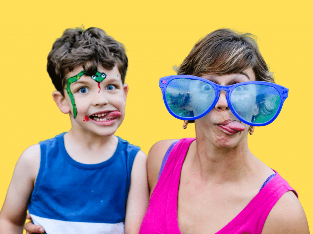 Mom wearing clown glasses and kid with face tattoo making silly faces.