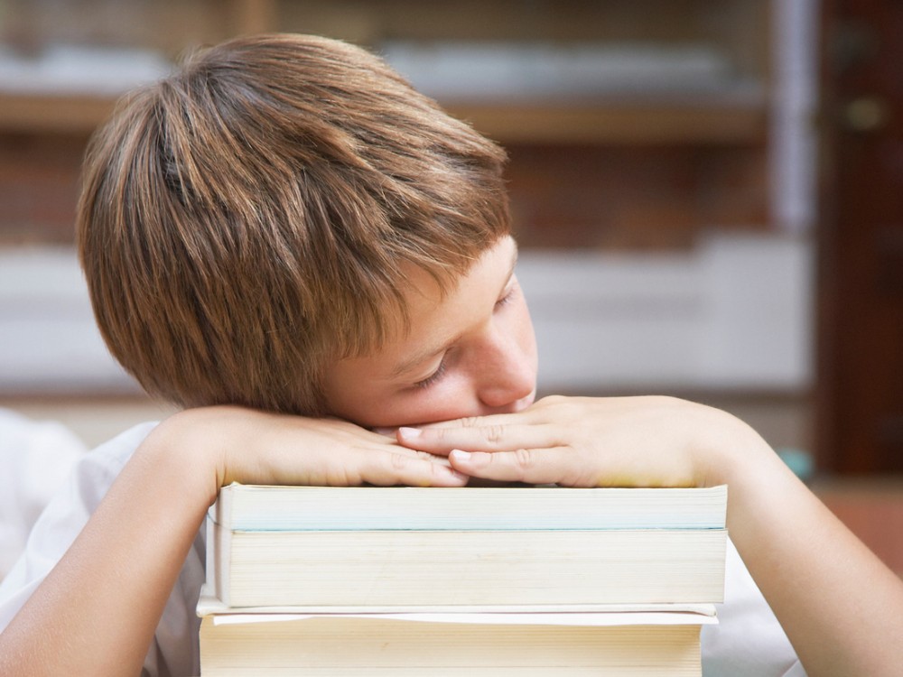 Student sleeping on a stack of books.