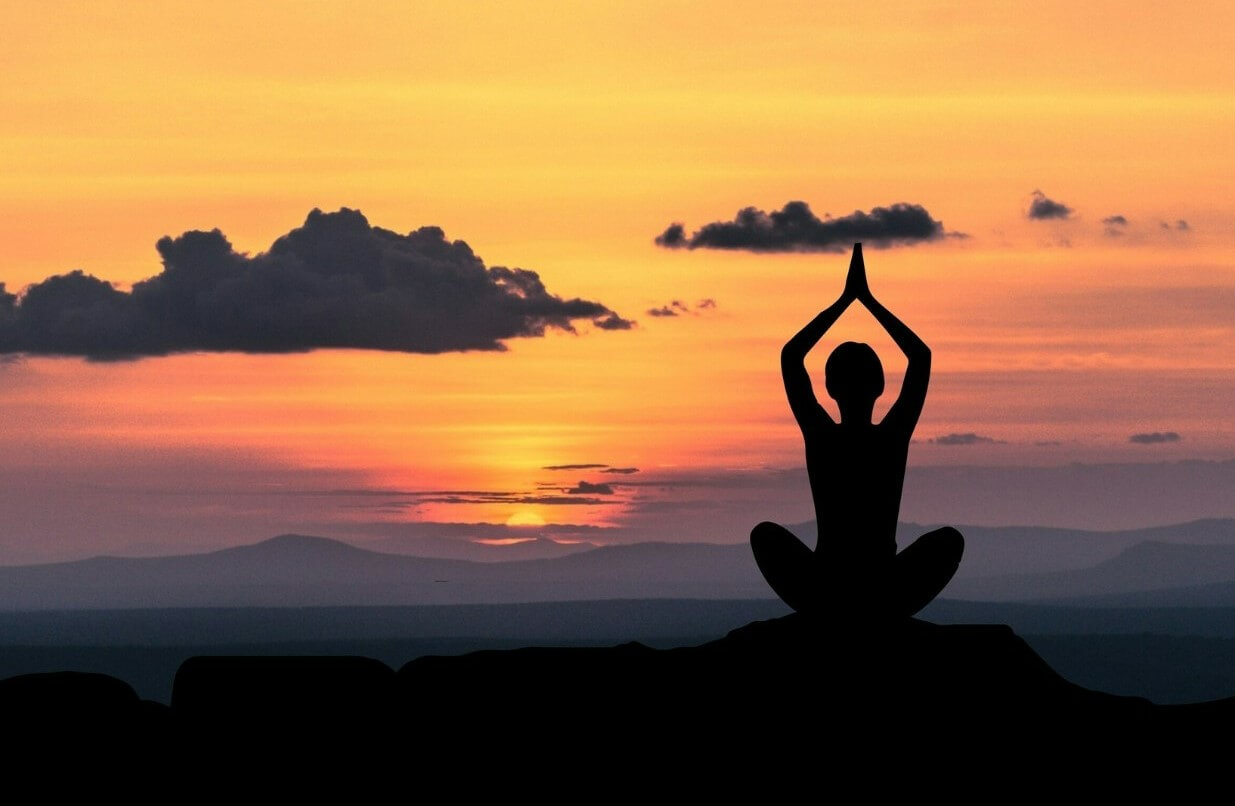 A teacher meditates in front of a beautiful sunset after quitting her teaching job.
