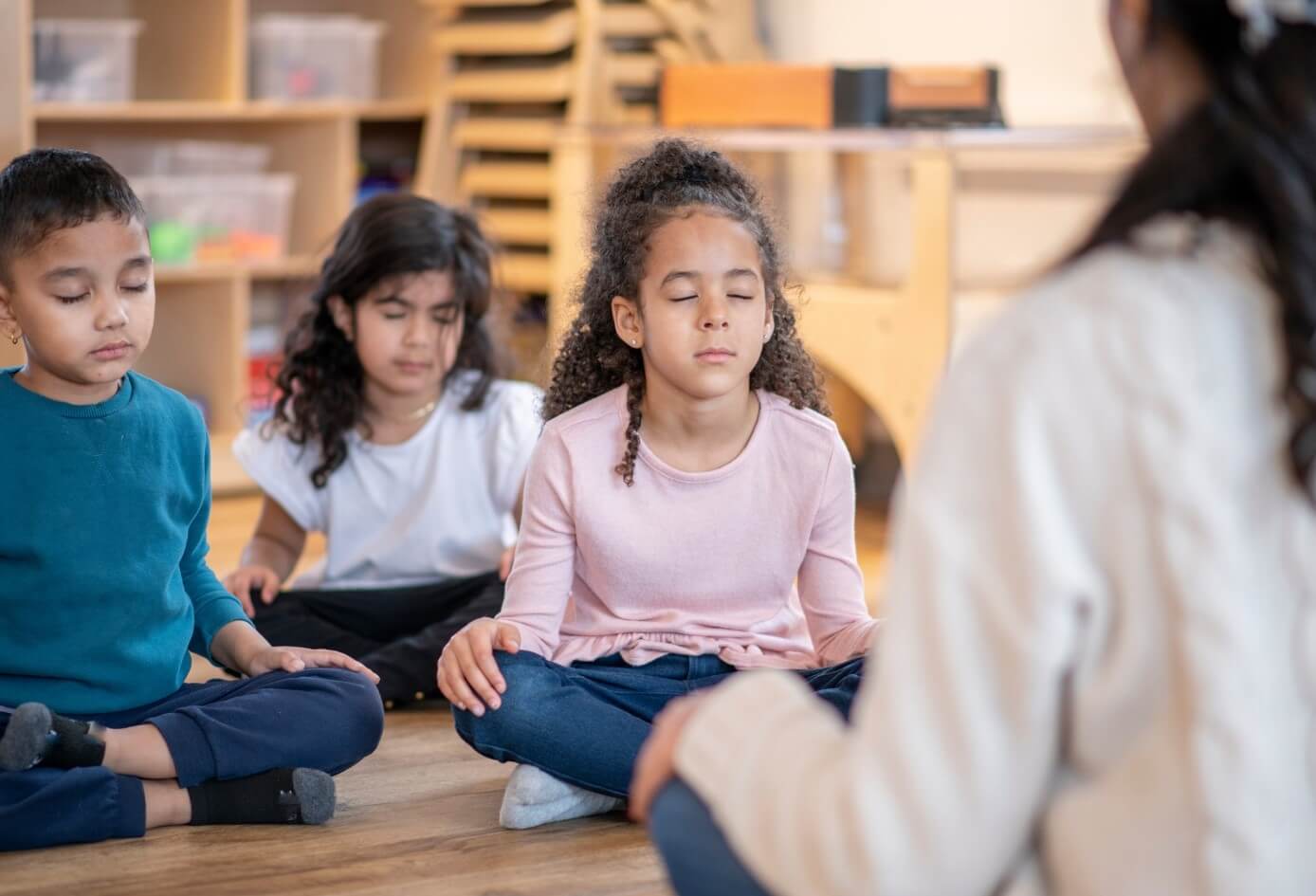 A teacher leads kids in a mindfulness meditation activity on her first day of teaching at a new school.