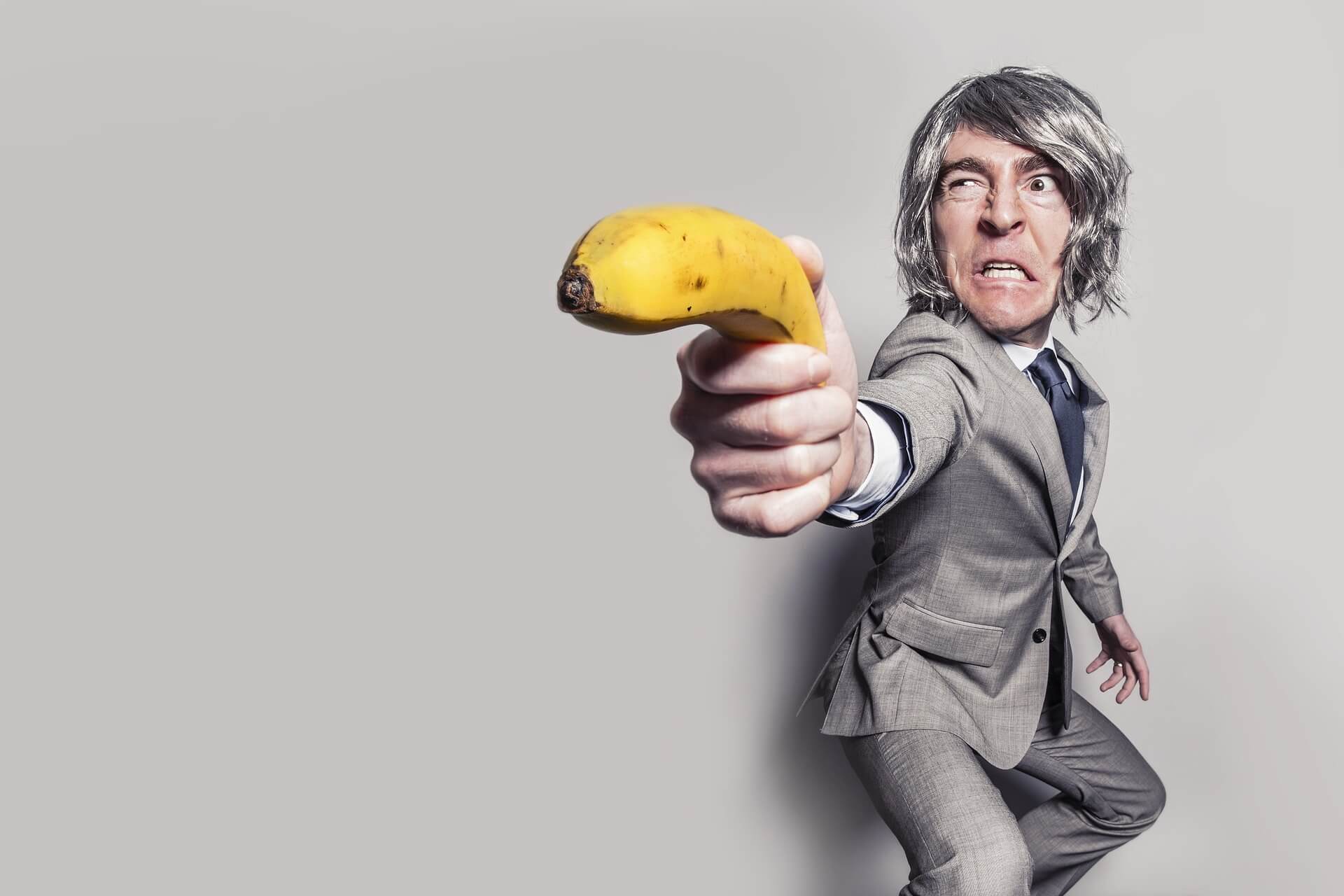 A teacher in a business suit wields a banana as a gun after burning out from going above and beyond.