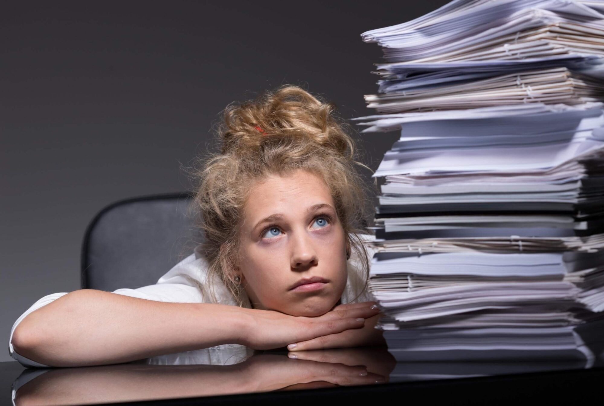 A teacher is overwhelmed staring at a huge pile of paperwork while considering quiet quitting.