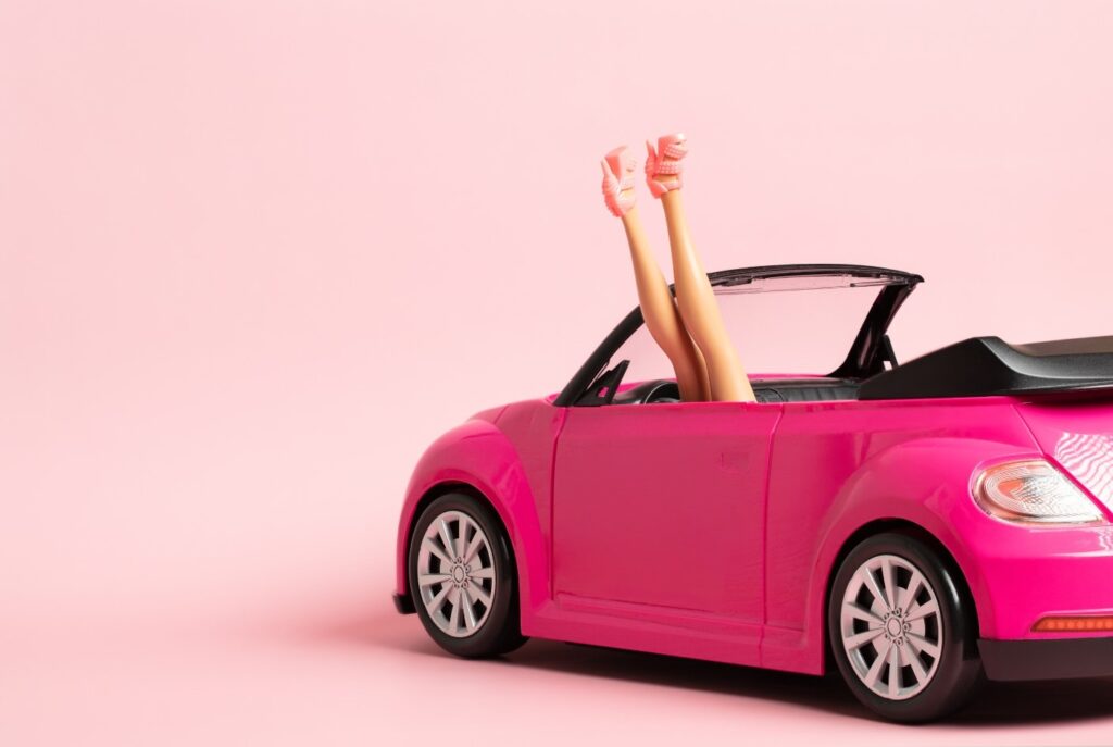 Barbie turned upside down in a pink car with her legs sicking out.