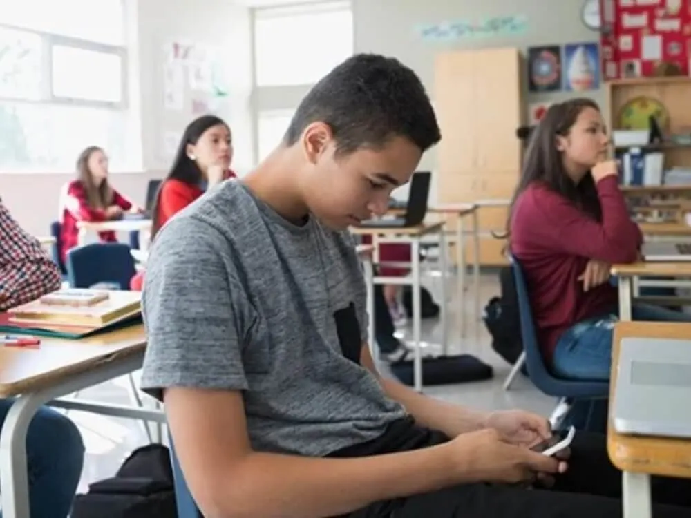 A distracted student on his smartphone in class.