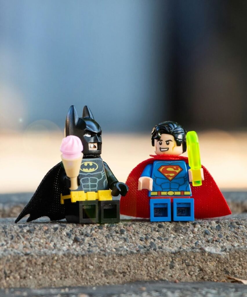 A Lego Batman and Superman eating ice-cream together.